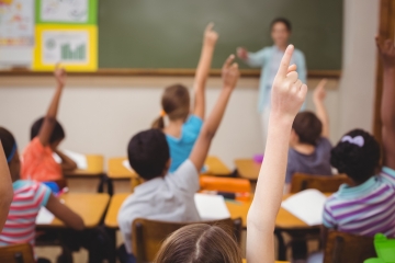 Students raising their hands in a school classroom