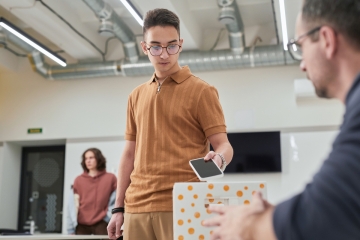 Student putting a cellphone in a box in a classroom