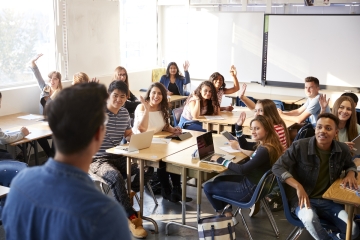 Students raising their hands in a school classroom