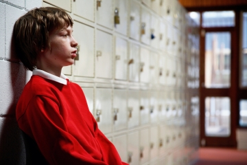 Upset teen boy in school hallway
