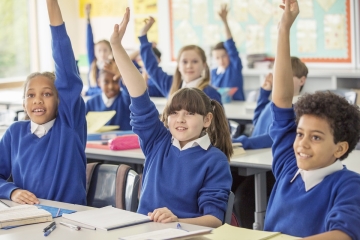 Students raising their hands in a school classroom