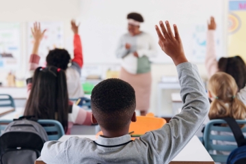 Students raising their hands in a school classroom