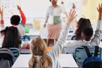 Students raising their hands in a school classroom