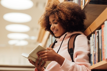 Student reading a book in a library