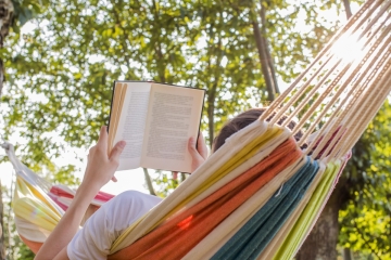 Person reading a book in a hammock 