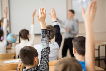 Students raising hands in the classroom