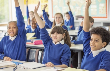 Students raising their hands in a school classroom