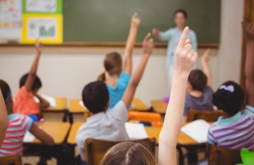 Students raising their hands in a school classroom