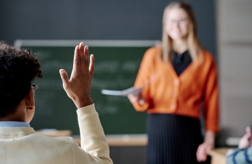 Student raising hand in a classroom