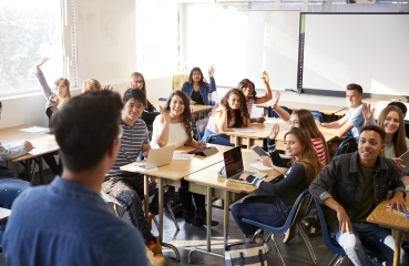 Students raising their hands in a school classroom