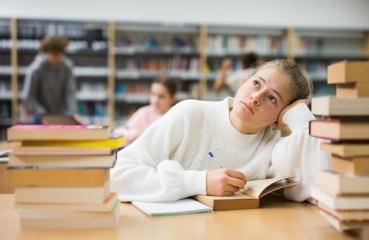 Bored college student reading book
