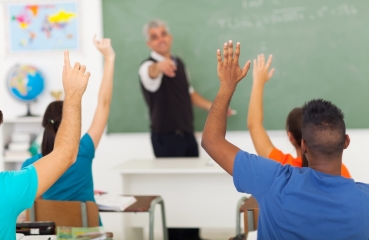 Students raising their hands in a school classroom