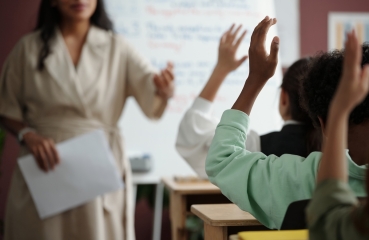 Students raising their hands in a school classroom