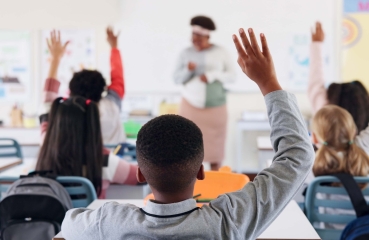 Students raising their hands in a school classroom