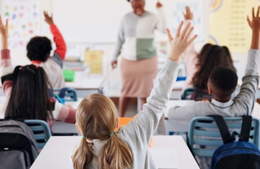 Students raising their hands in a school classroom