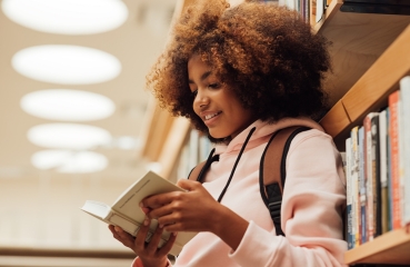 Student reading a book in a library