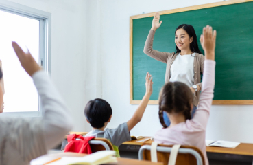 Teacher and students with hands raised