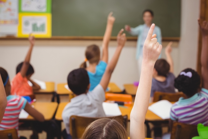 Students raising their hands in a school classroom