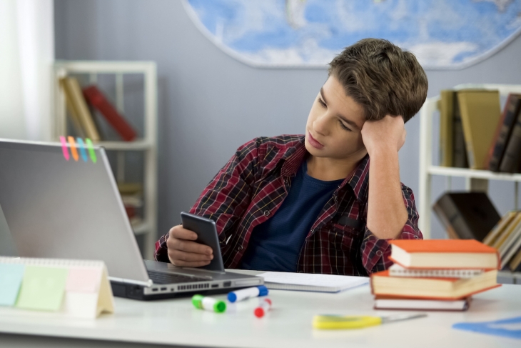 Bored teen student at home doing homework