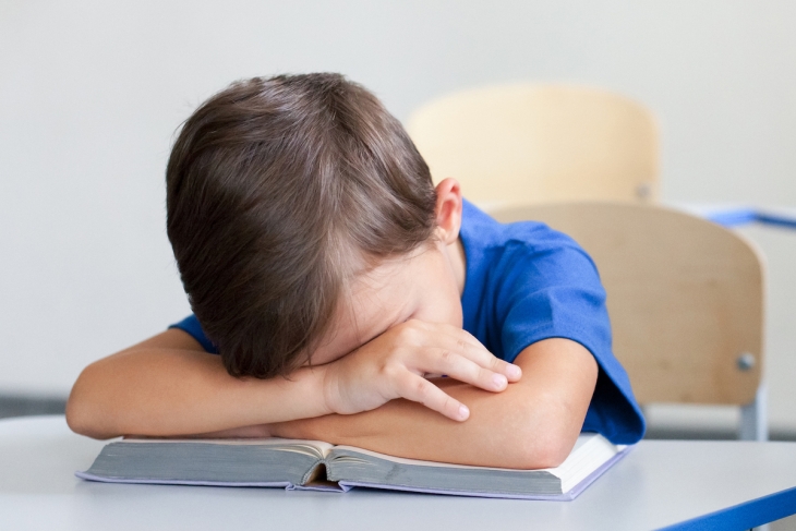 Upset child reading in a classroom