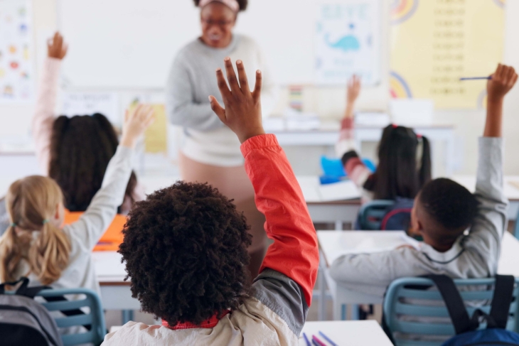 Students raising their hands in a school classroom