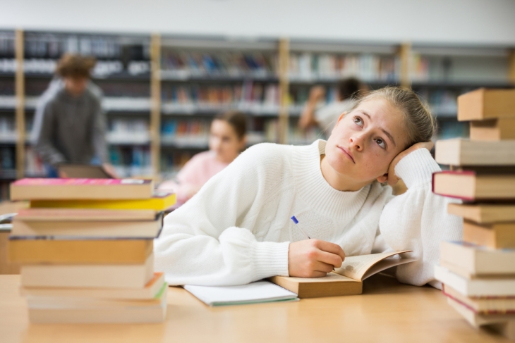 Bored college student reading book