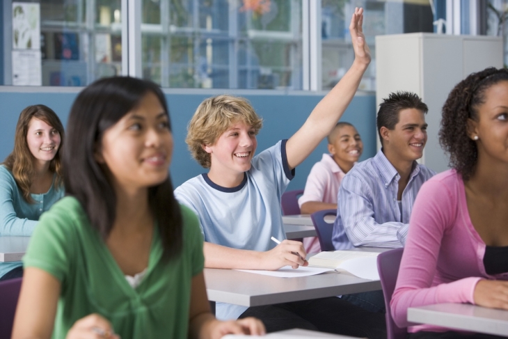 Teenagers raising hands in a classroom