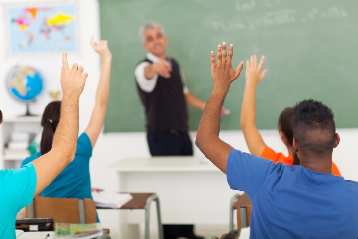 Students raising their hands in a school classroom