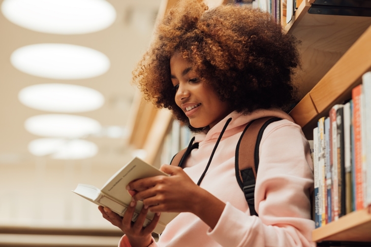 Student reading a book in a library