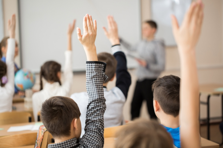 Students raising hands in the classroom