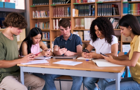 Teenagers in library looking at phones